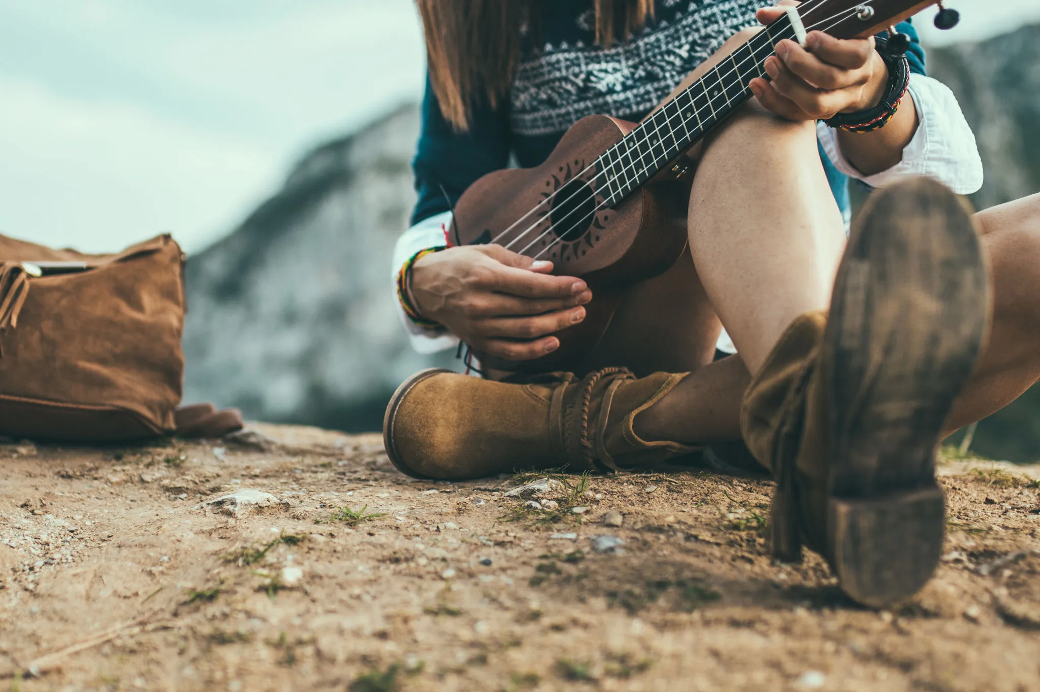 Person sitzt auf einem Felsen und spielt Ukulele